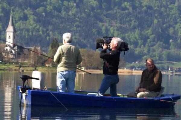 Drei Personen im Boot beim Angeln auf dem Ossiacher See, mit einem Kameramann, der das Angeln dokumentiert.